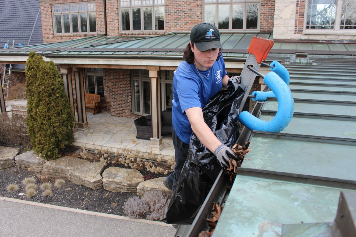 Employee clearing leaves out of an eavestrough